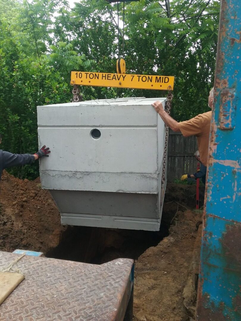 Workers lowering concrete septic tank.