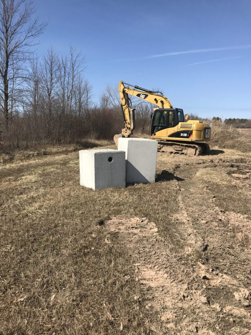 Excavator near concrete blocks in field.