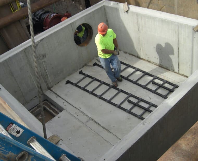 A construction worker standing on top of a concrete structure.